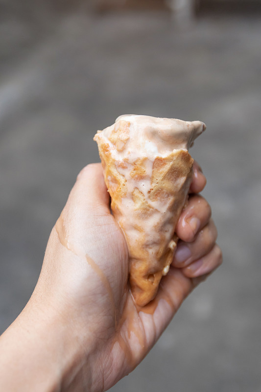 女人手拿融化的咖啡杏仁味冰淇淋在华夫蛋筒图片下载