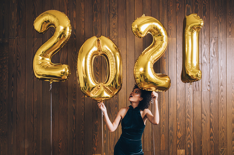 新年晚会:一个快乐的女人在2021年的金色气球下跳舞庆祝新年图片下载