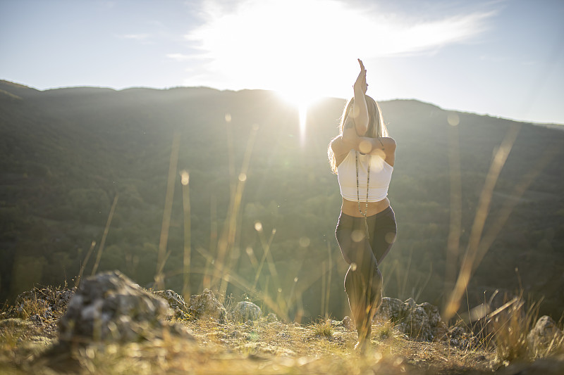 女运动员练习鹰的姿势瑜伽。在清晨日出的时候欣赏大自然。图片下载