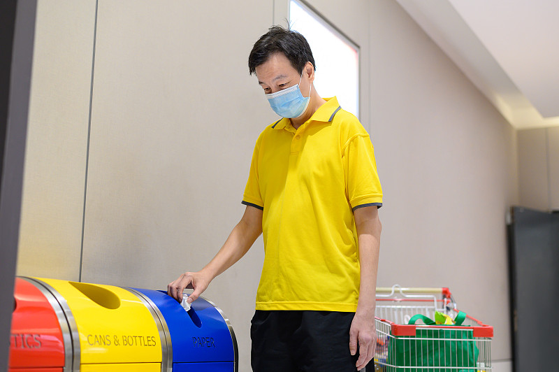 中亚成人将垃圾放入废物分类回收箱内图片素材