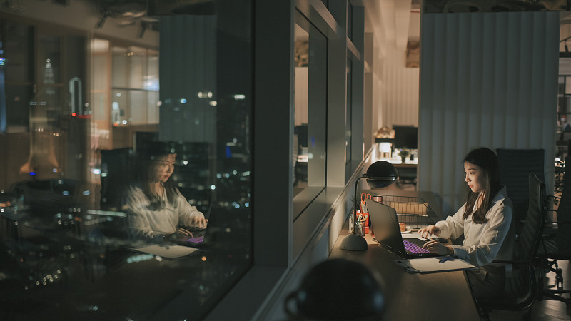 亚洲华裔女白领在办公室工作到深夜独自赶财务报告图片素材