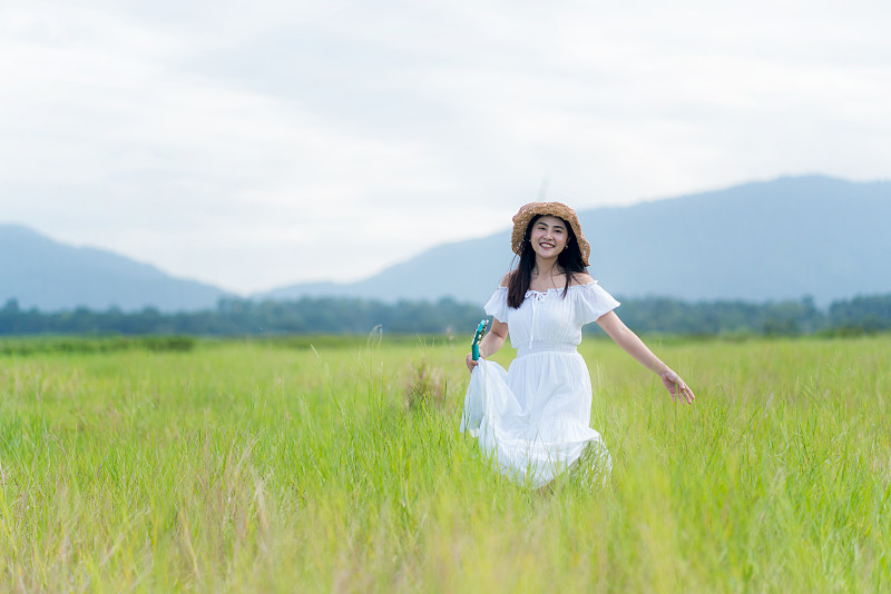 美丽无忧无虑的亚洲女人在草地。轻松、自由的工作风格。图片下载