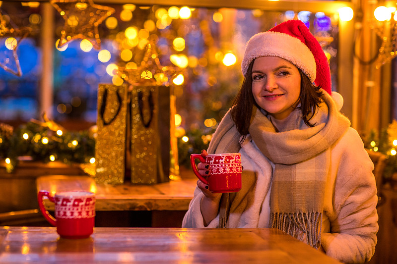 一个美丽的女人在一个温暖的装饰咖啡馆在冬天图片下载