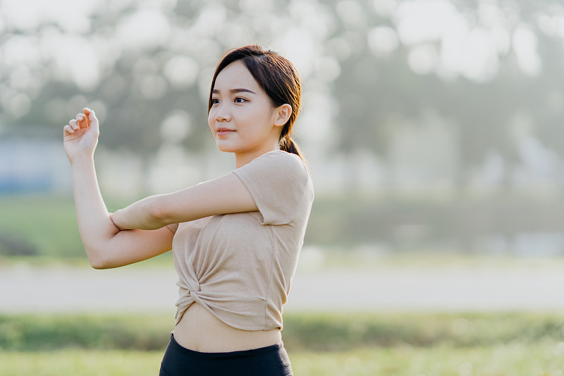 快乐的年轻亚洲妇女做伸展运动在公共公园图片下载