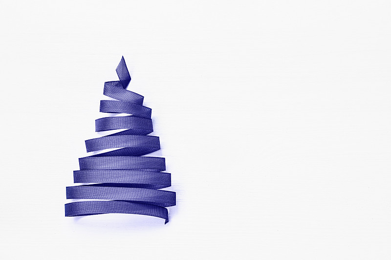 白色背景上用淡紫色丝带做成的圣诞树。非常Peri 2022颜色。本空间图片素材