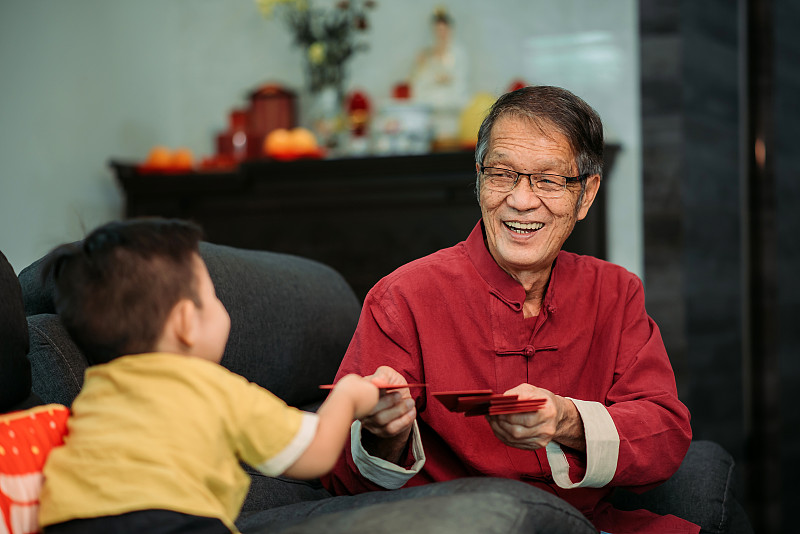亚洲华人微笑的老人在生活大厅给孙子在中国新年红包图片下载