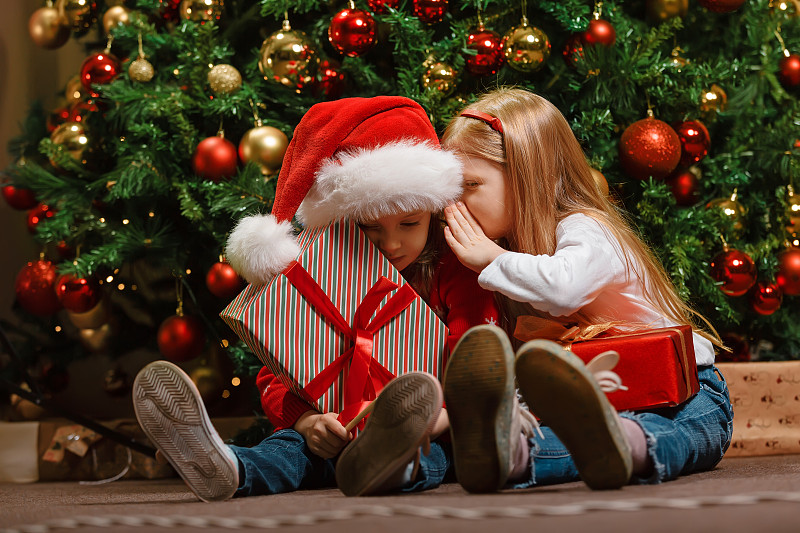 孩子们分享关于圣诞老人在圣诞树下发现的珍贵礼物的秘密图片下载