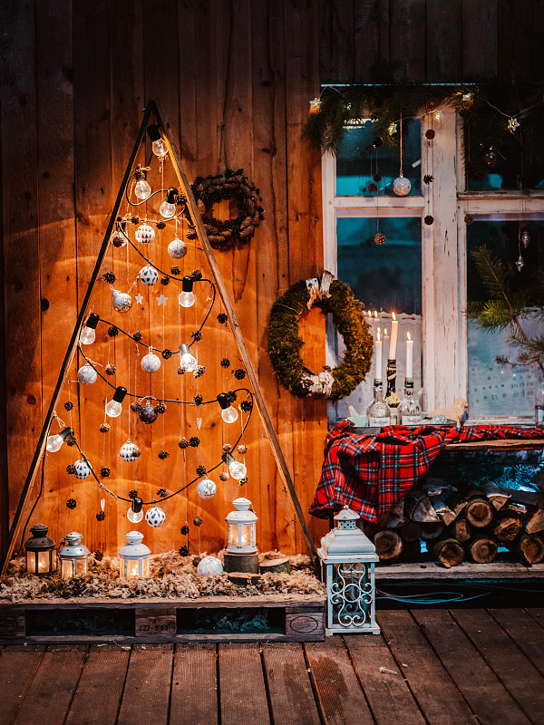 带有美式圣诞装饰的乡村别墅的冬季外观。白雪覆盖的院子里有门廊、树、白色长凳和老式木制雪橇。图片下载