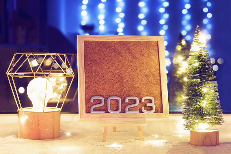 2023年新年的数字在圣诞树和彩灯旁边的漂亮画架上。2023年新年和圣诞节酒店预订的折扣和促销活动。2023年销售。生产日历2023。图片下载