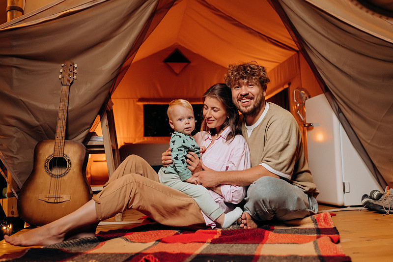 快乐的家庭和可爱的宝宝一起玩耍，在夏天的晚上一起露营。户外休闲休闲的豪华露营帐篷。生活方式的概念图片下载