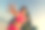 一个穿着红色比基尼，戴着墨镜的女人在金色的日落中沿着海滩散步，背景是山脉。摄影图片