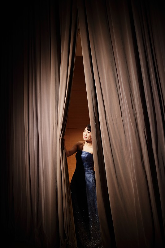 从音乐厅舞台的窗帘中窥视的女性图片下载