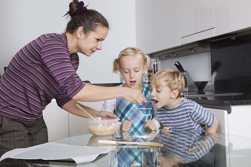 母亲和孩子们在厨房烘焙和品尝饼干面糊图片下载