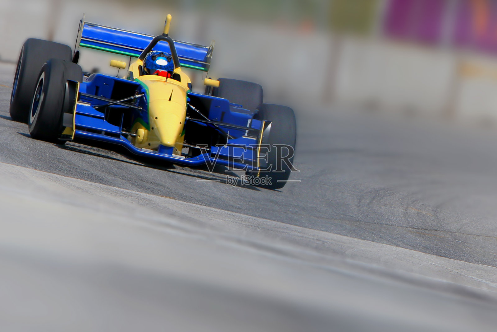 一辆蓝色和黄色的赛车在跑道上行驶照片摄影图片