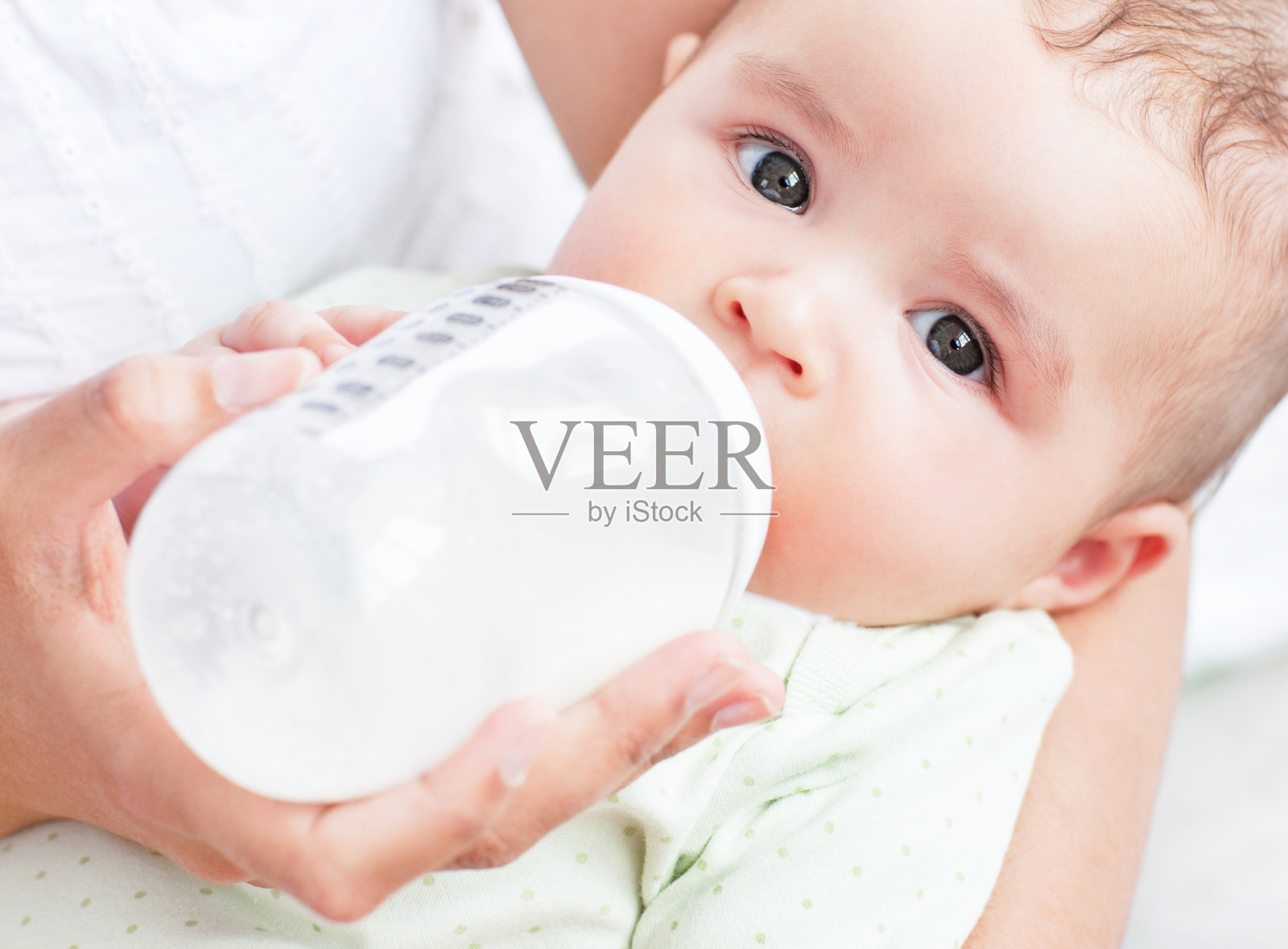 一个婴儿在母亲怀里喝牛奶的特写照片摄影图片
