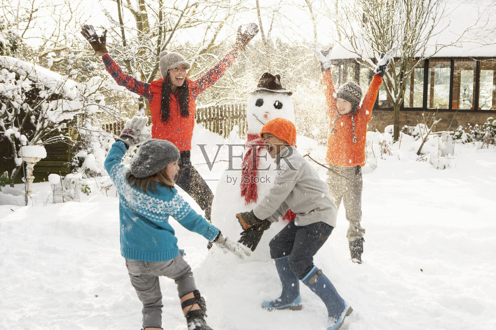 快乐的妈妈和孩子们在院子里堆雪人照片摄影图片