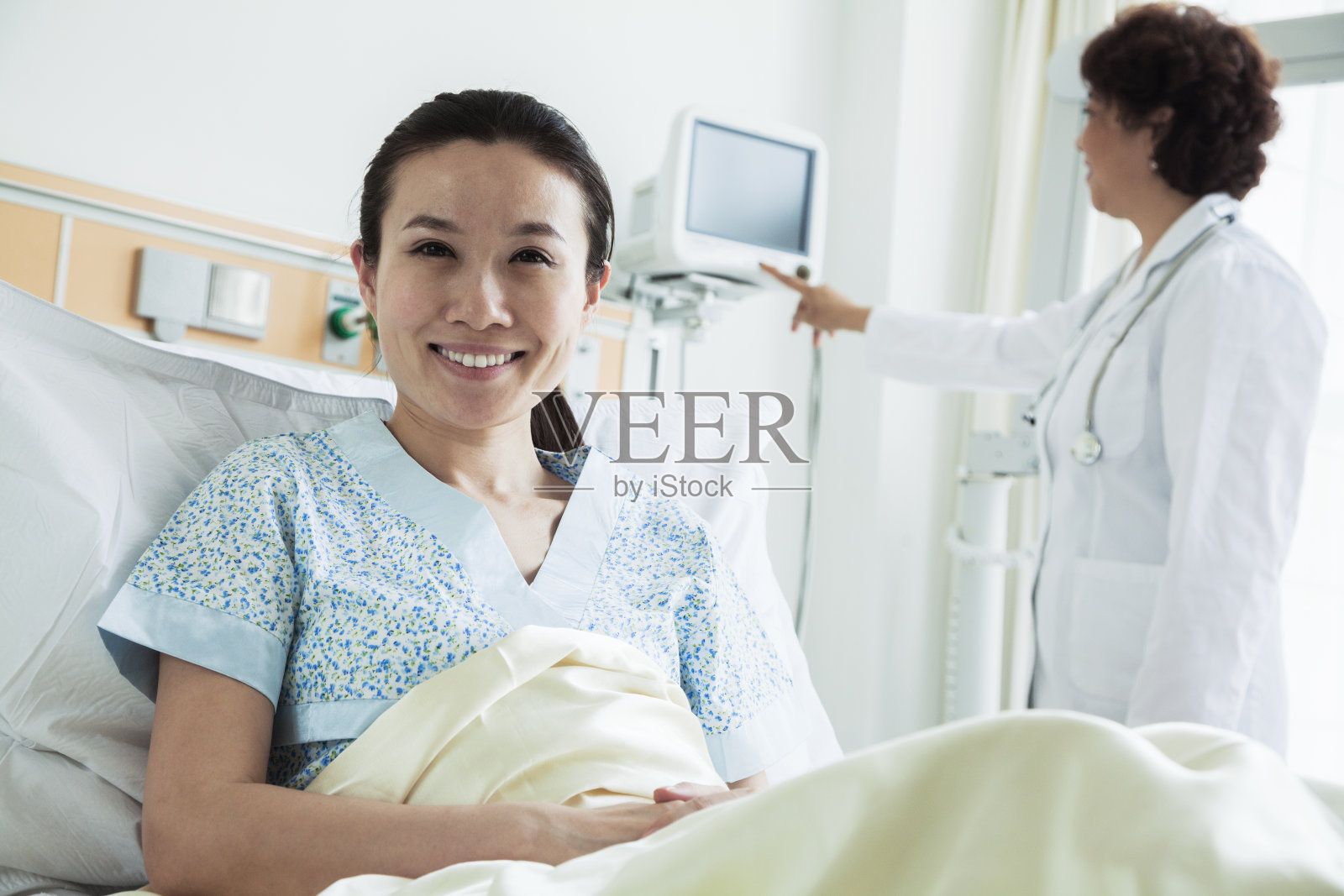 微笑的女病人坐在医院的病床上照片摄影图片