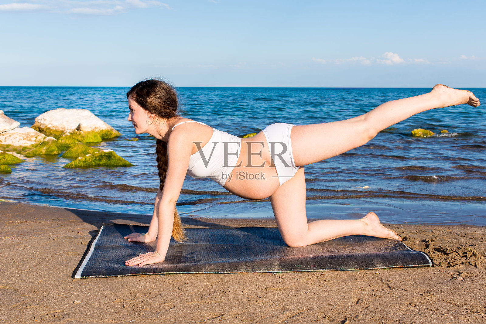 孕妇在运动胸罩上瑜伽在海上pose照片摄影图片
