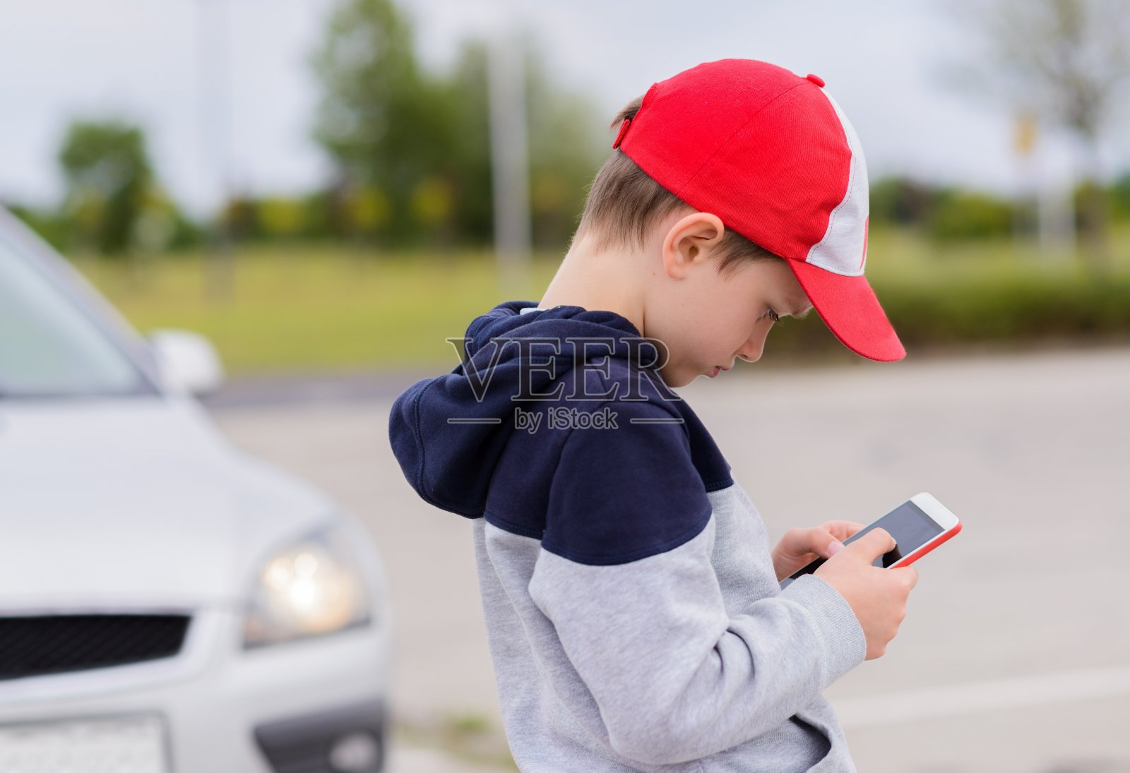 孩子在街上玩手机游戏照片摄影图片