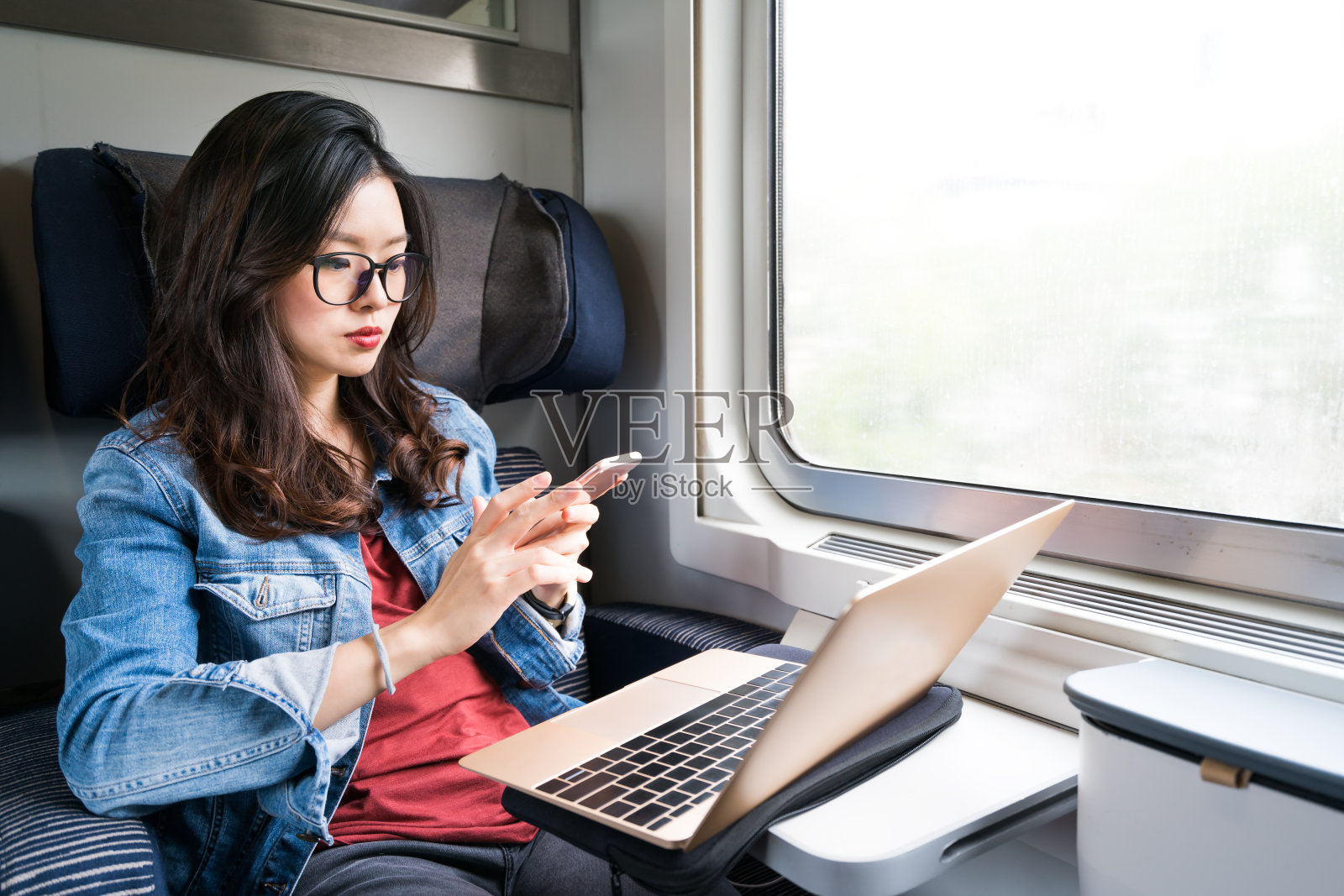 可爱的亚洲女人在火车上使用智能手机和笔记本电脑照片摄影图片