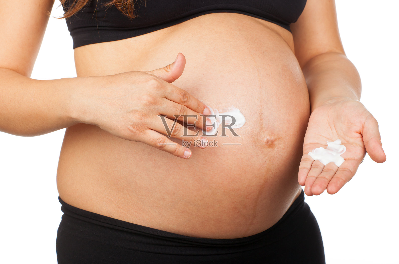 孕妇按摩她的腹部与软膏拉伸照片摄影图片