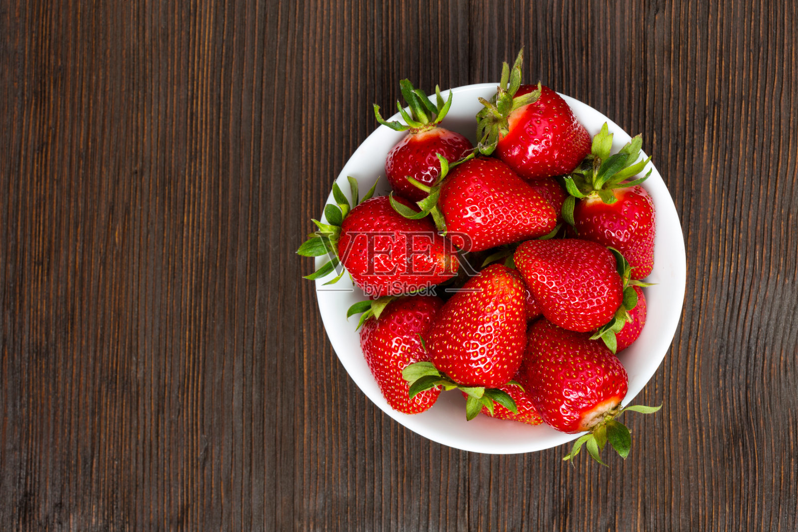 新鲜成熟的草莓放在一个简单的白色碗里照片摄影图片