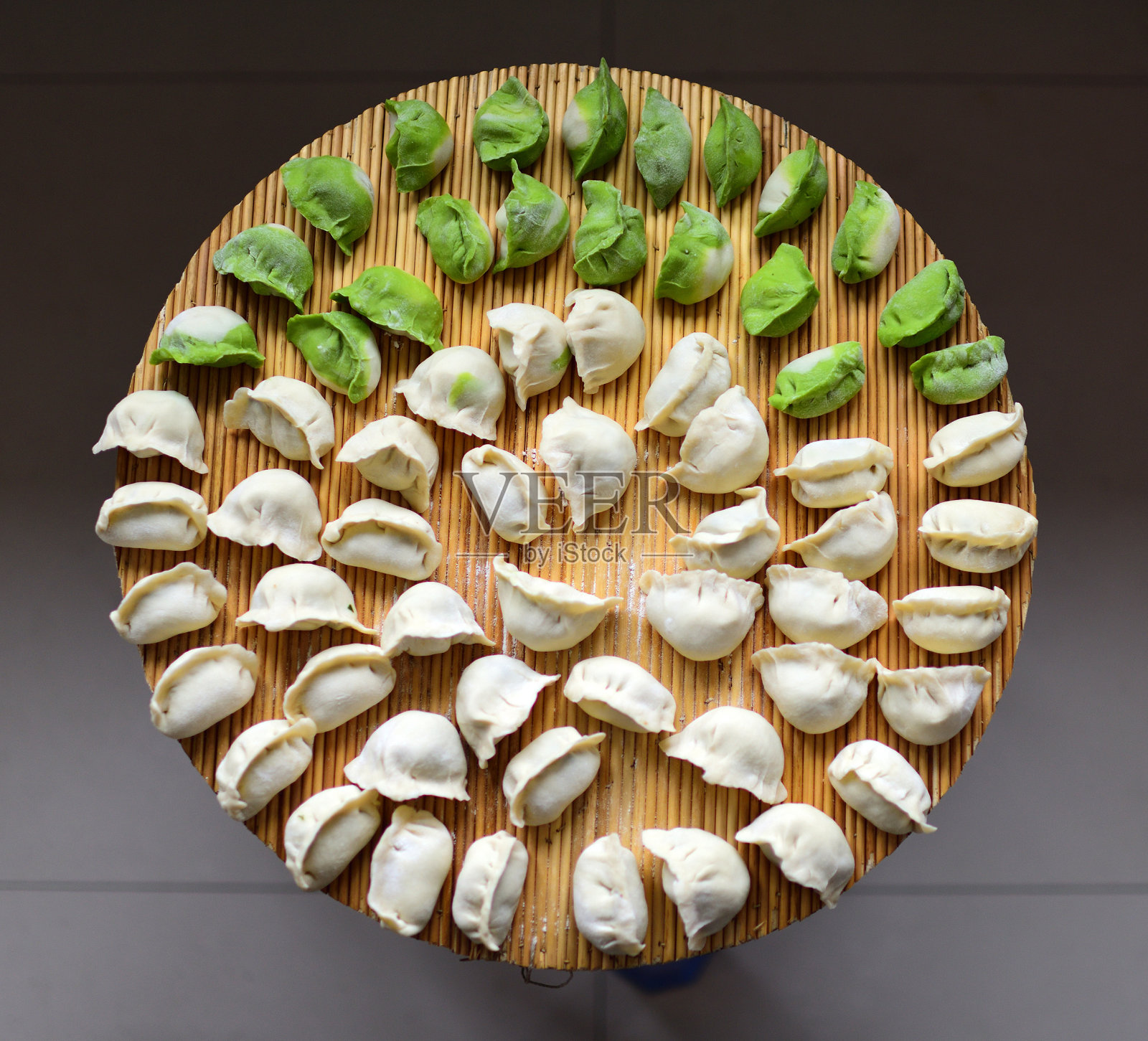 绿色和白色的中国生饺子(饺子)在天然高粱茎垫。照片摄影图片