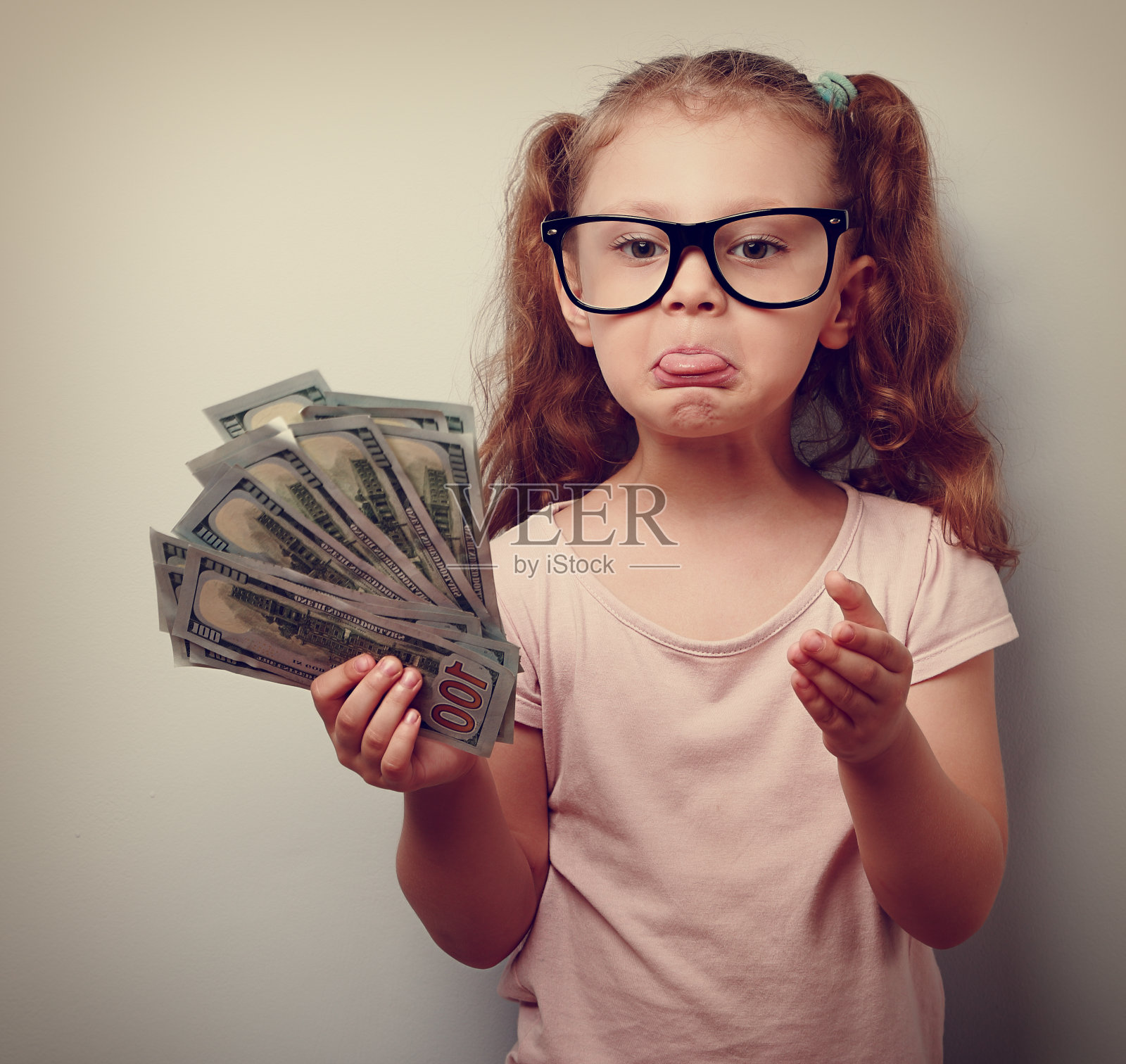 沮丧的小女孩戴着眼镜拿着美元照片摄影图片