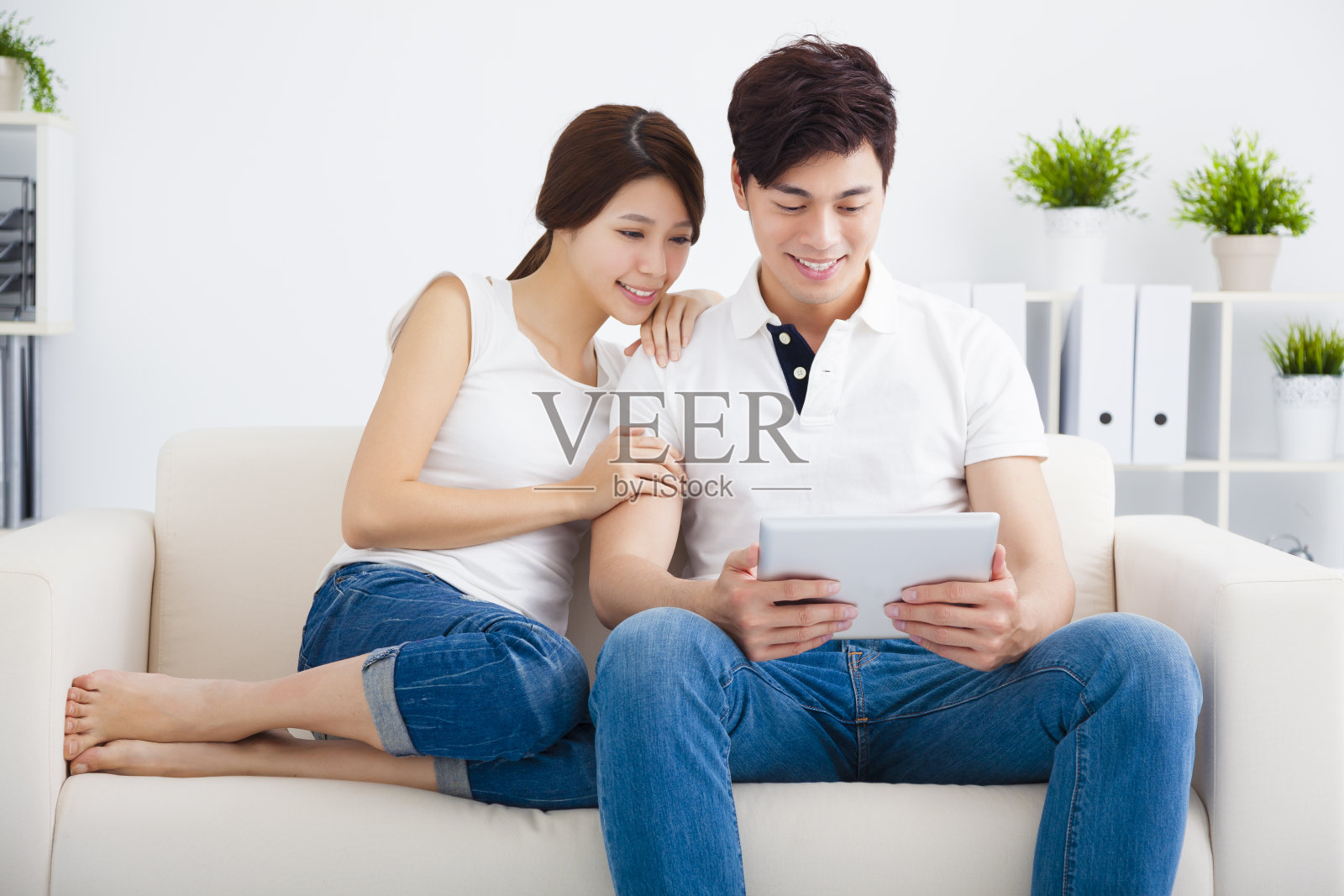 一对亚洲夫妇在沙发上玩平板电脑照片摄影图片