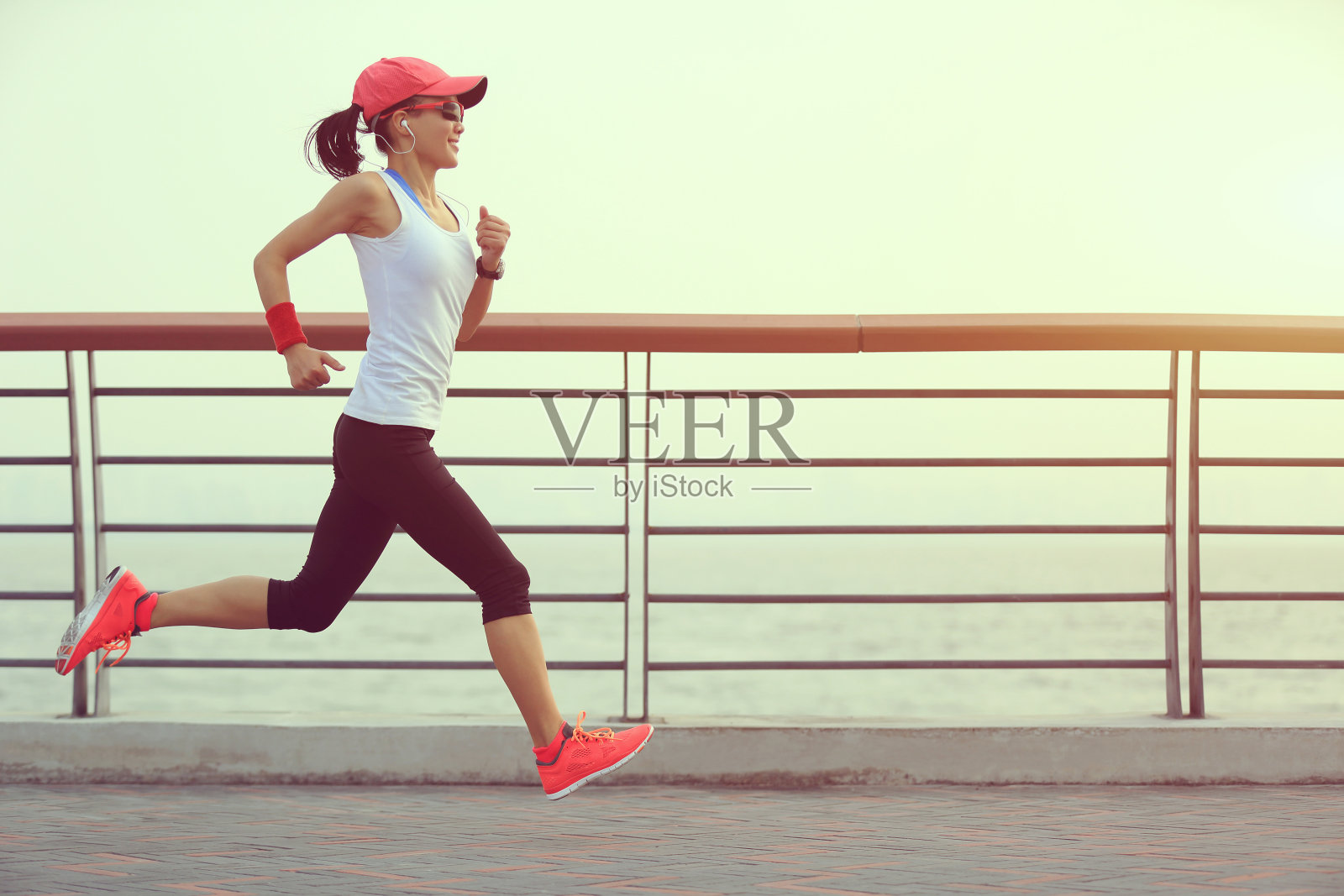 年轻的健身女性跑步在日出的海边照片摄影图片