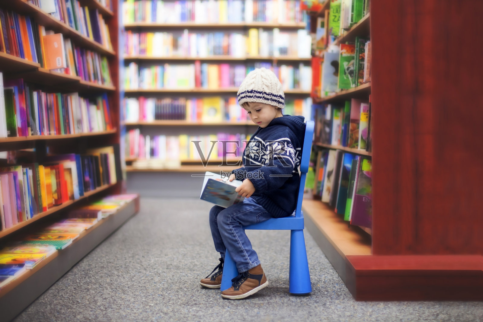 可爱的小男孩，坐在书店里照片摄影图片