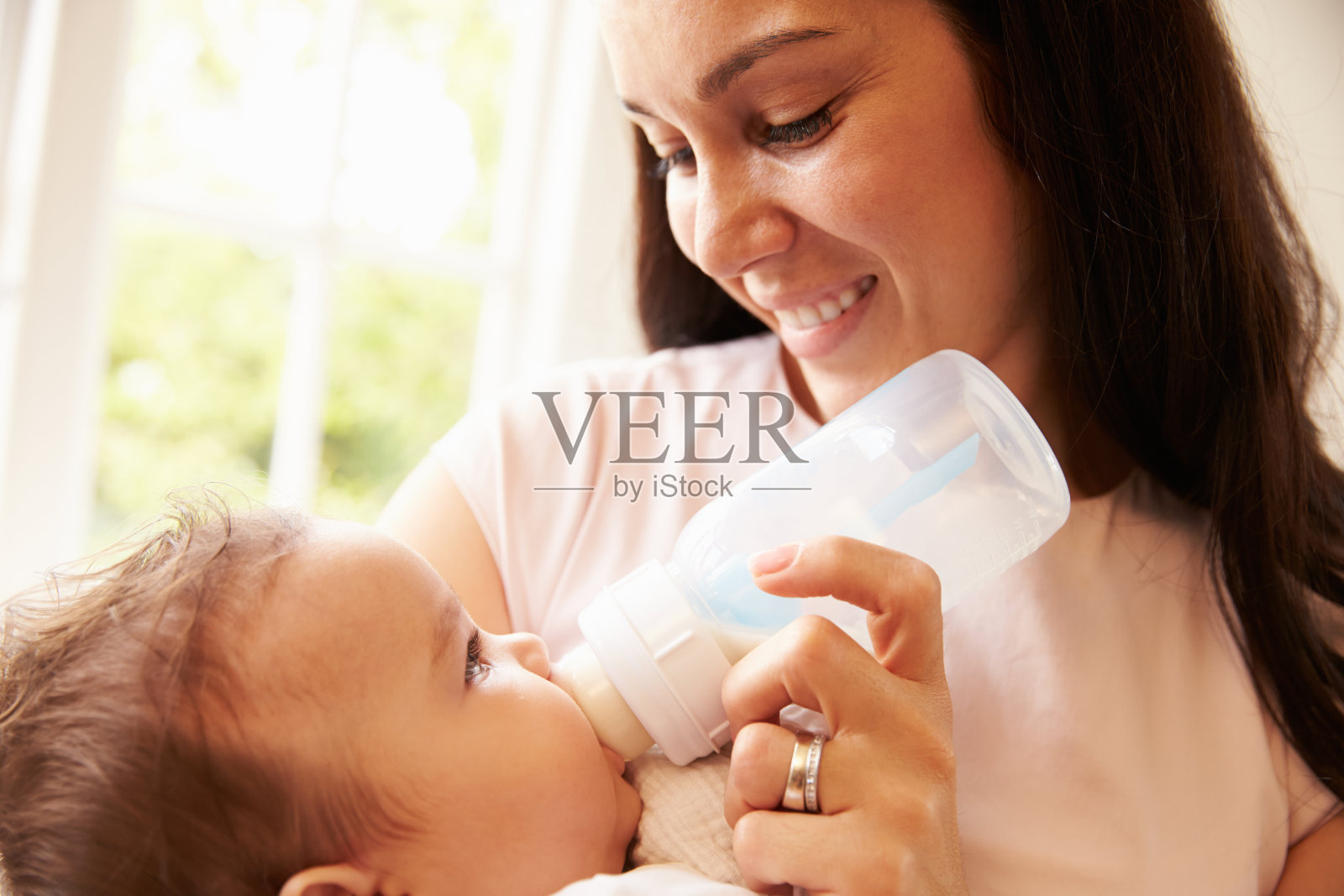 母亲在家用奶瓶喂男婴照片摄影图片