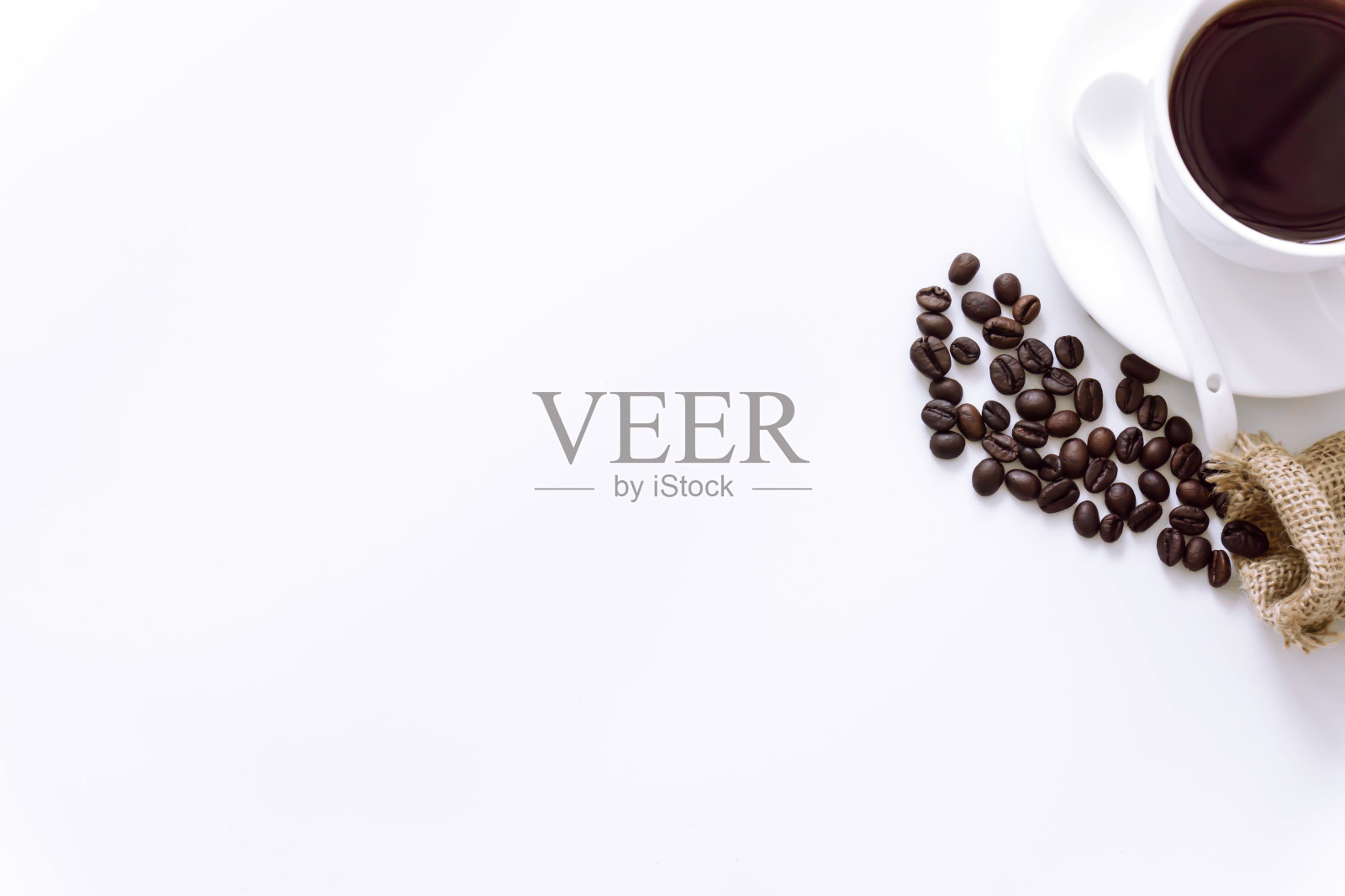 一杯咖啡围绕着咖啡豆在白色的背景。照片摄影图片