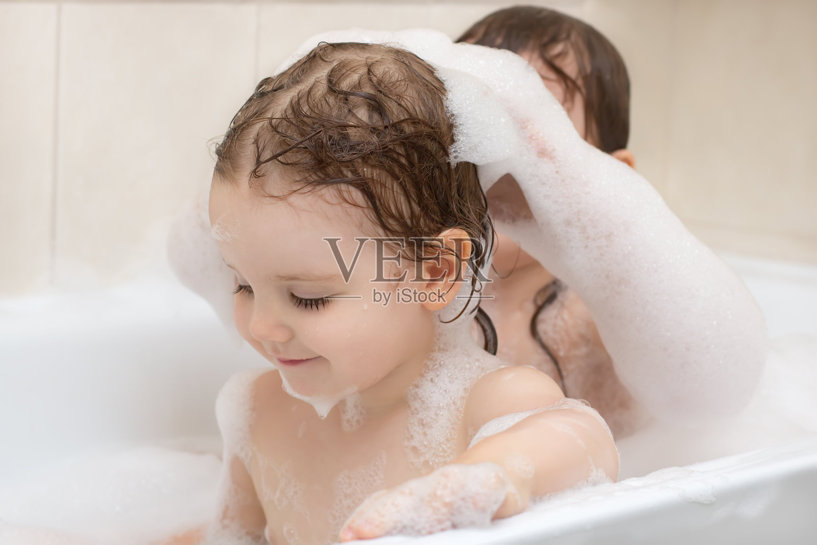 两个可爱的小女孩正在用肥皂泡沫洗澡照片摄影图片
