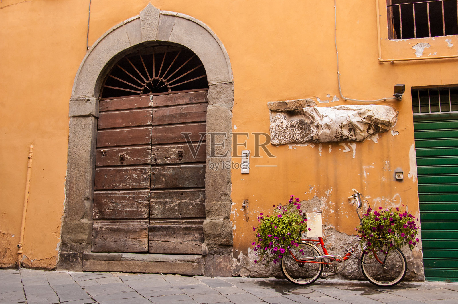一辆装满鲜花的红色自行车站在中世纪的门前照片摄影图片