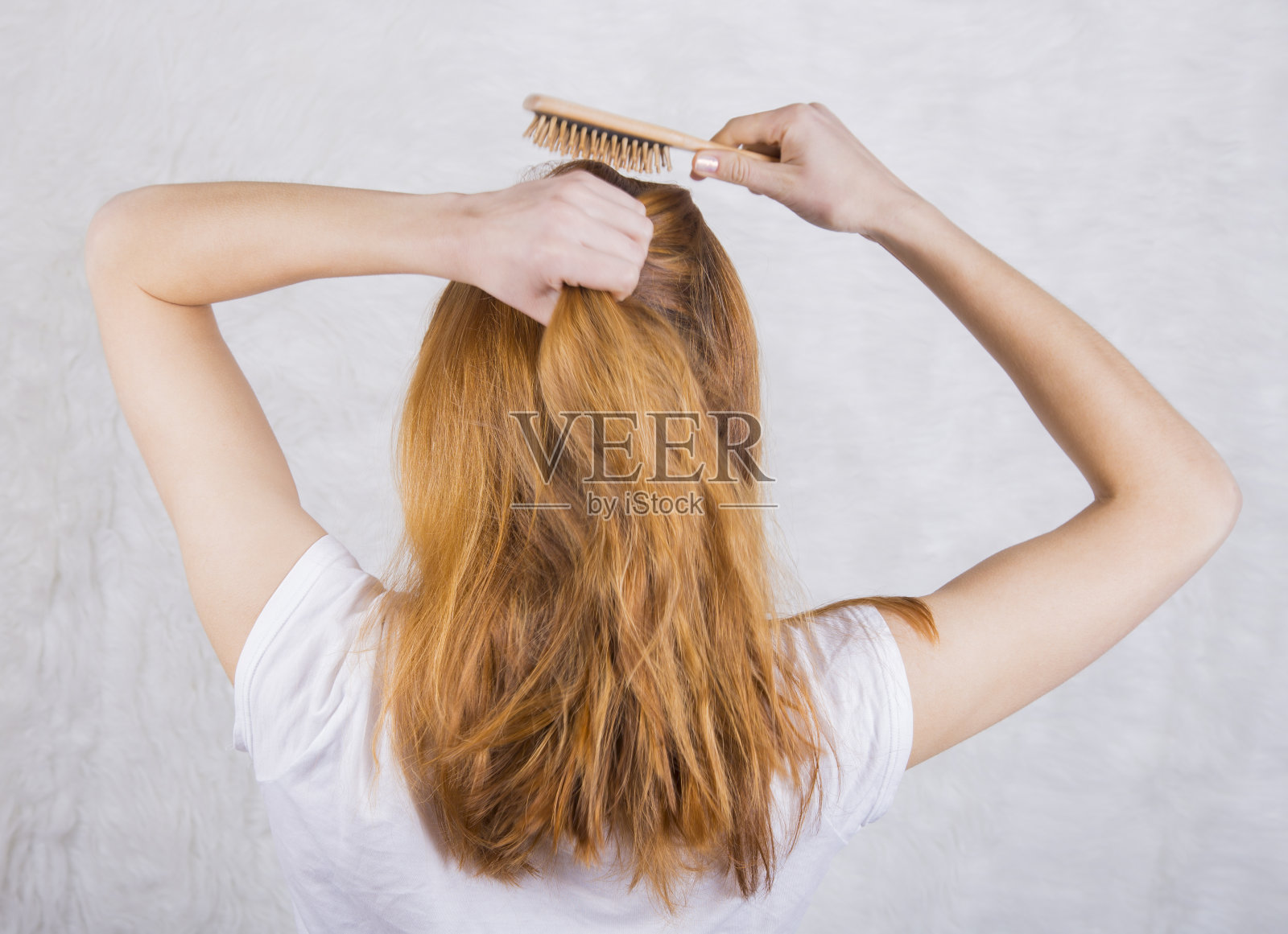 红头发的年轻女子用木梳子梳头照片摄影图片