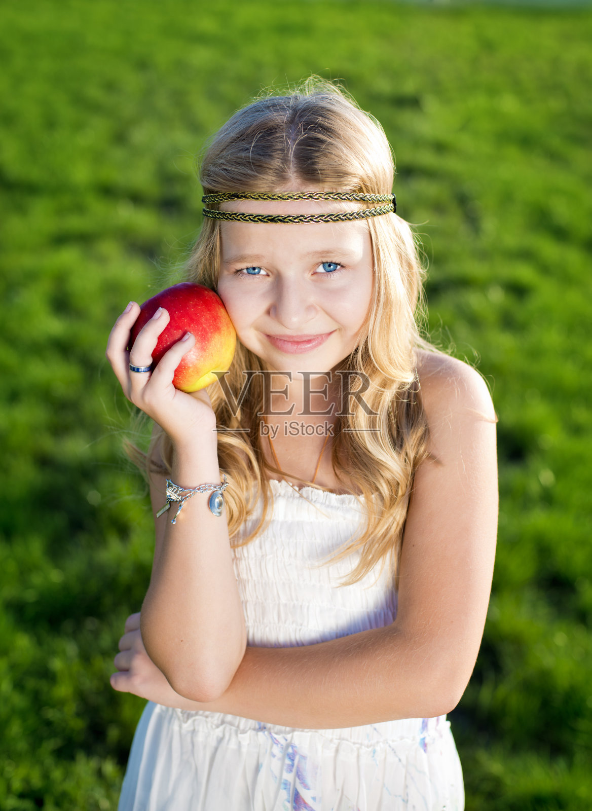 草地上有一个红苹果的漂亮小女孩照片摄影图片