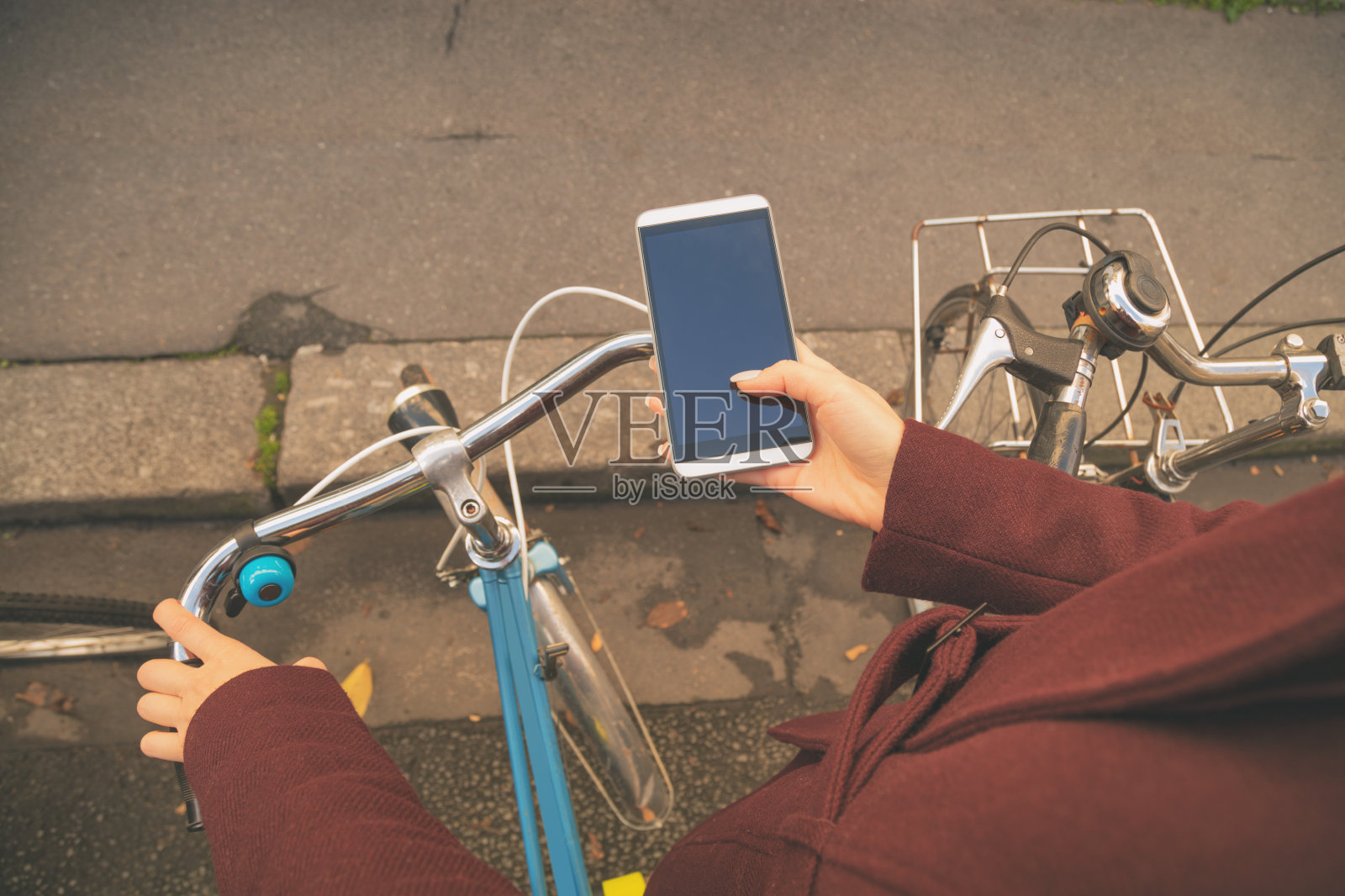 女孩在自行车旁边用手机。照片摄影图片