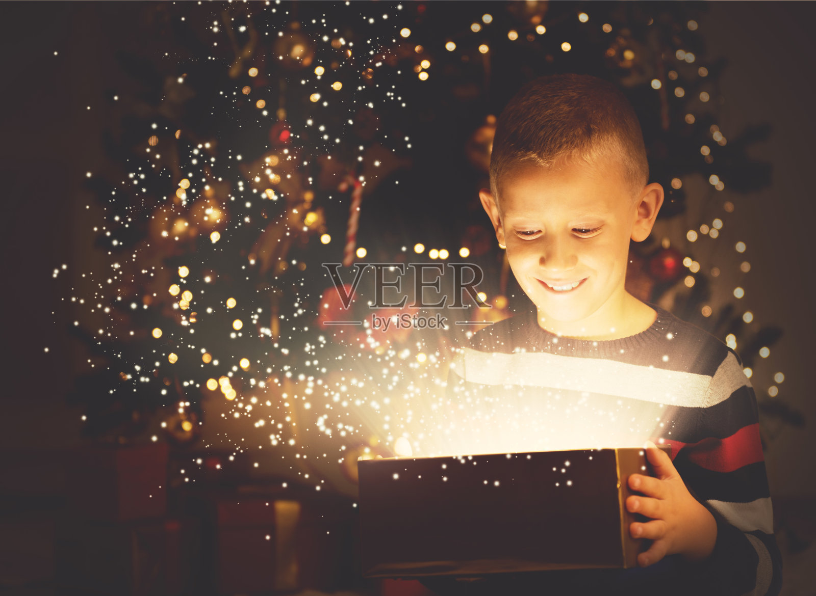 可爱的男孩在平安夜打开一份神奇的礼物照片摄影图片