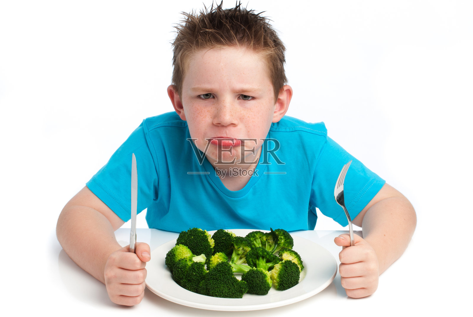 坏脾气的小男孩不喜欢吃花椰菜。照片摄影图片