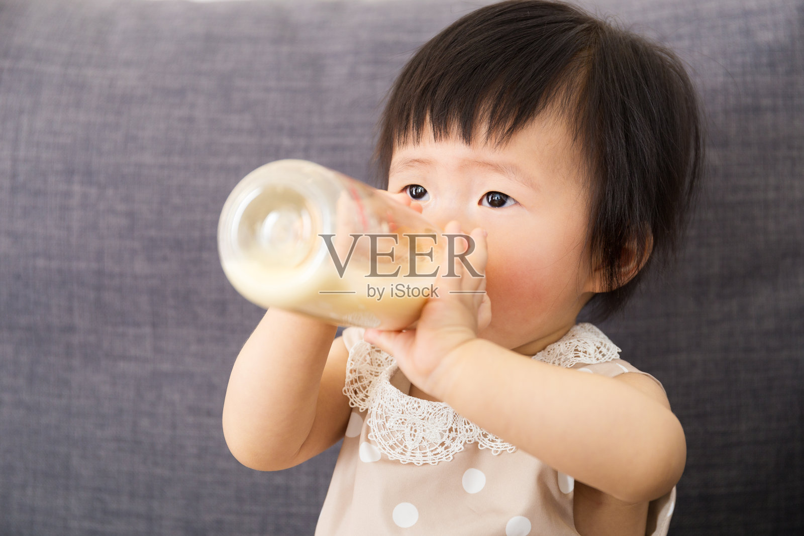 一个亚洲小女孩喝着一瓶牛奶照片摄影图片