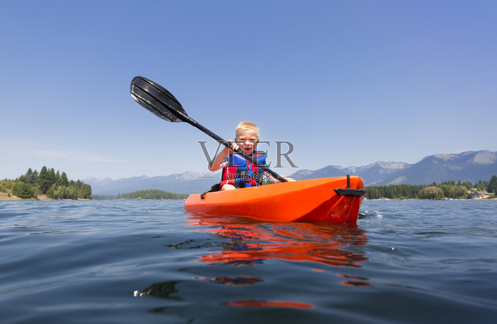 一个小男孩在一个美丽的山湖上划着皮划艇照片摄影图片