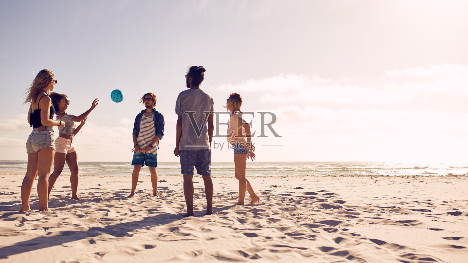 一群朋友在沙滩上玩球照片摄影图片