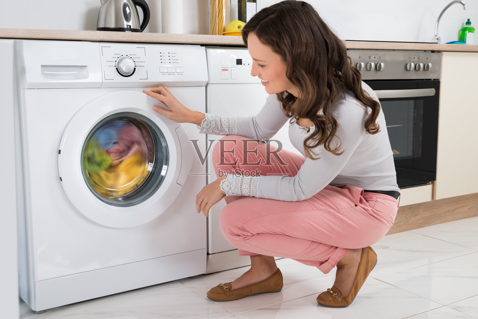 女人看着衣服在洗衣机里旋转照片摄影图片