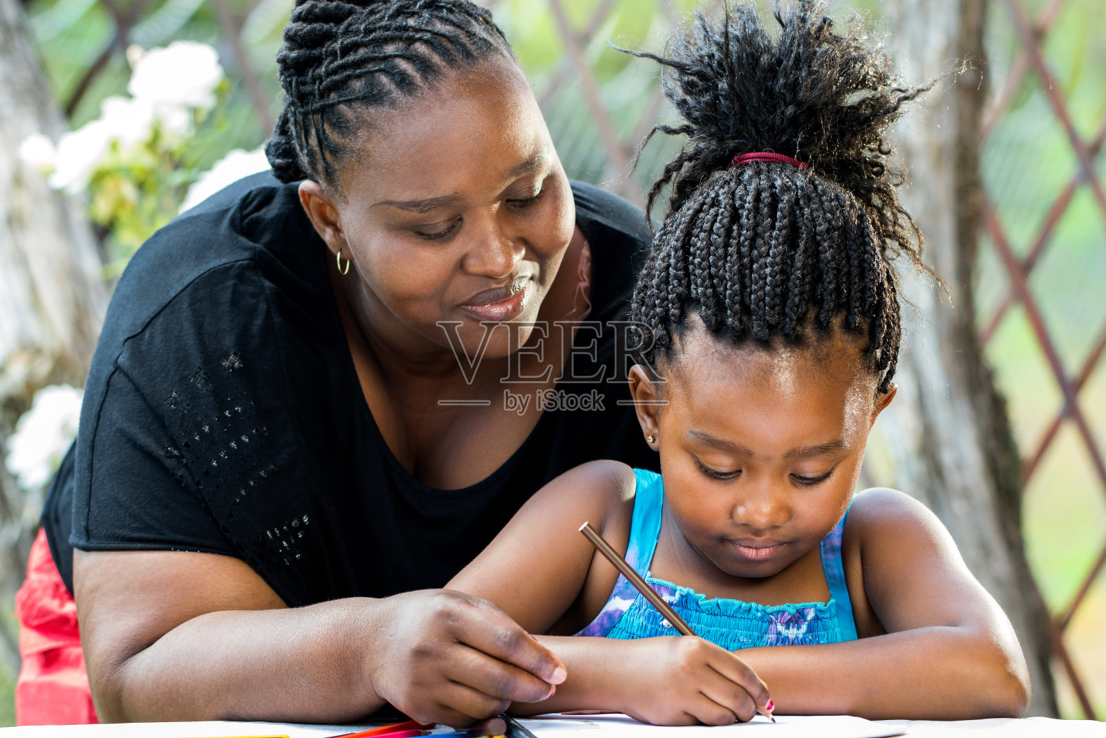 非洲母亲监督女儿写作。照片摄影图片