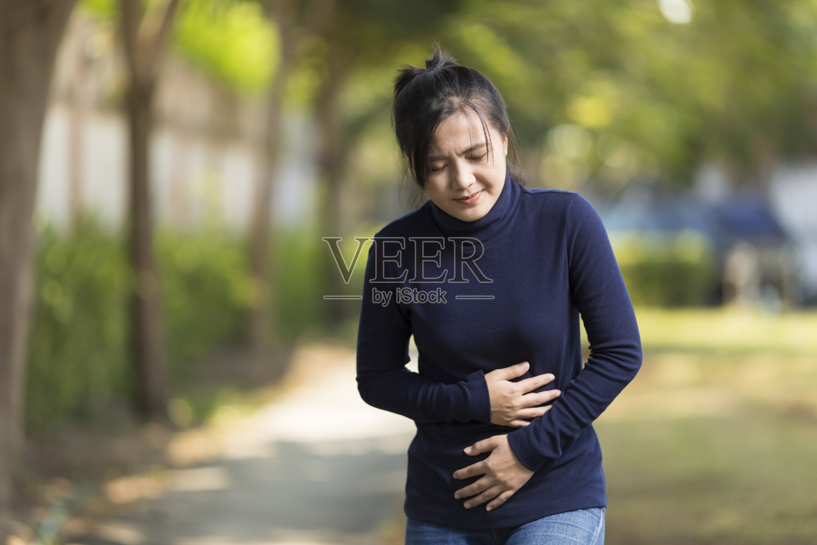 女人在公园胃痛照片摄影图片