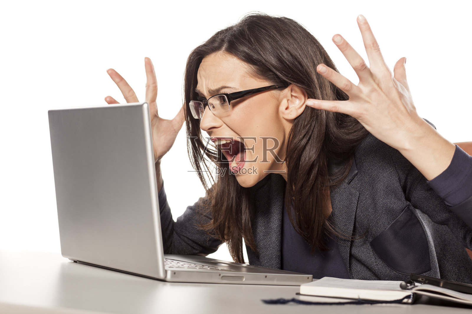 愤怒的年轻女商人对着她的笔记本电脑大喊大叫照片摄影图片