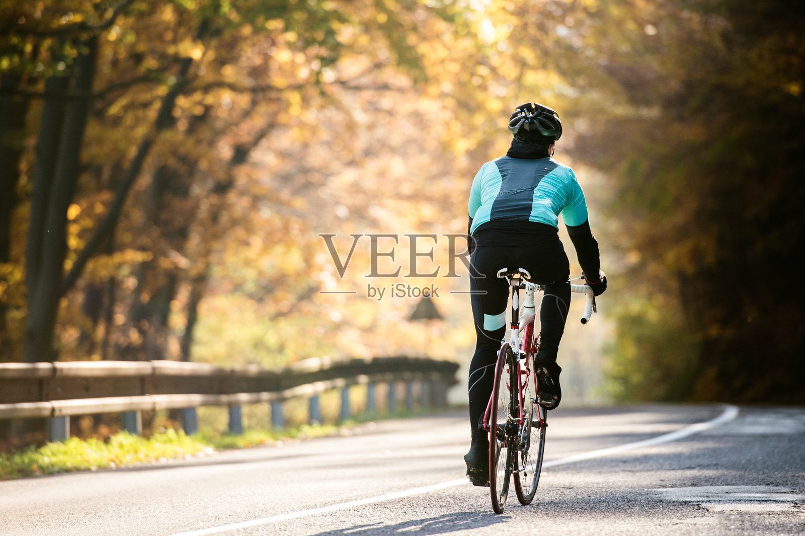 在阳光明媚的秋日里，年轻的运动员在户外骑自行车照片摄影图片