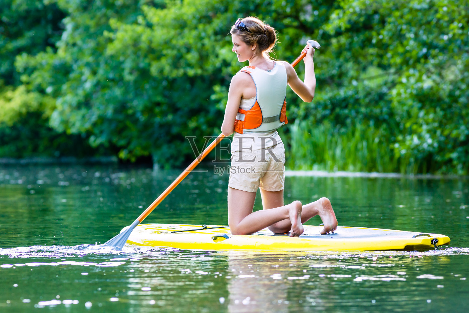 女人用立桨板在河上划水照片摄影图片