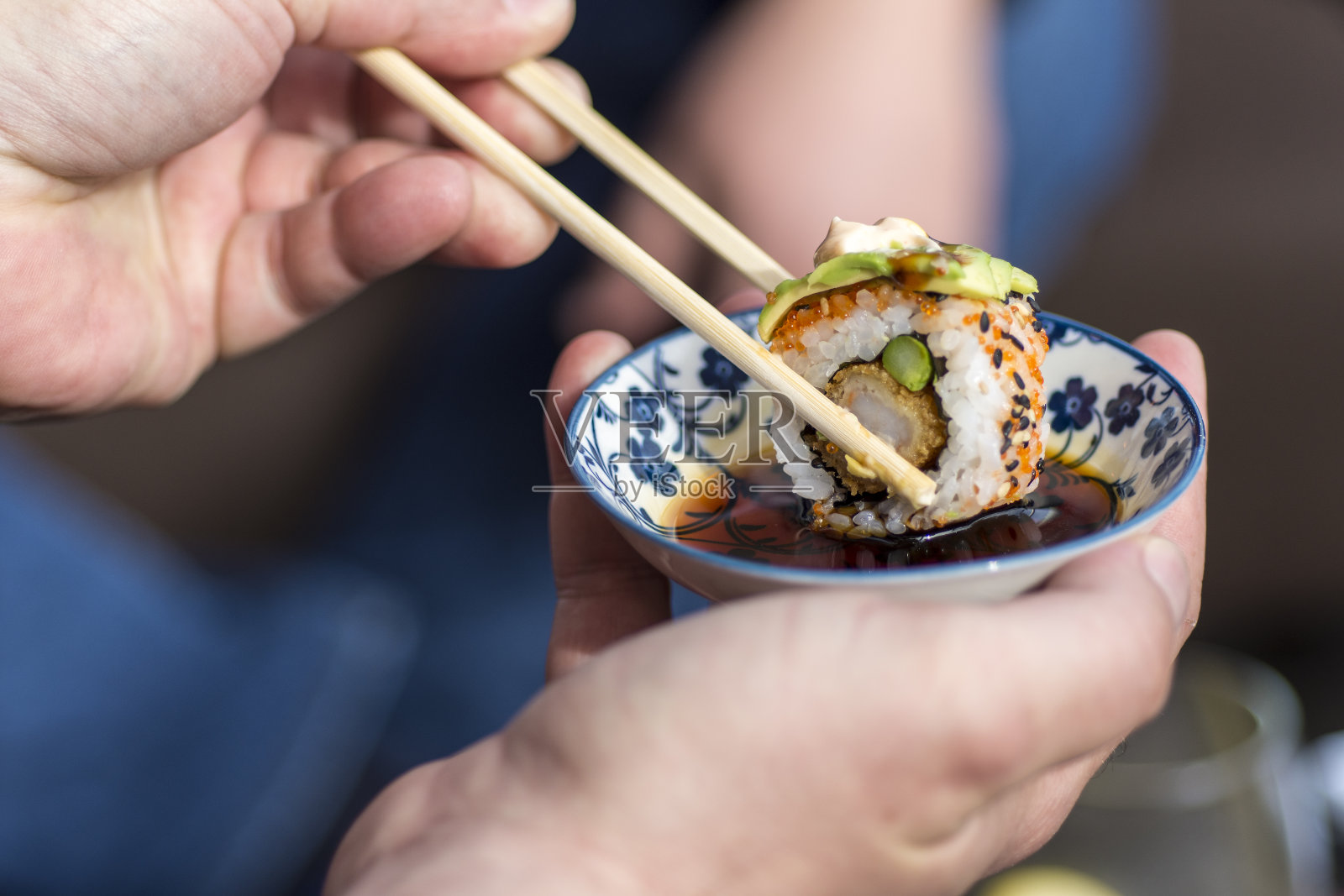 手握筷子蘸寿司卷酱油照片摄影图片